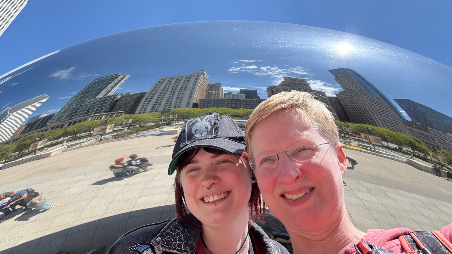 Two people taking a selfie in front of the Cloud Gate sculpture in Chicago.