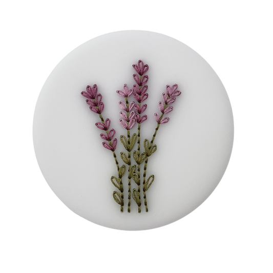 A completed embroidery kit depicting a bouquet of flowers arranged on a round acrylic disk.