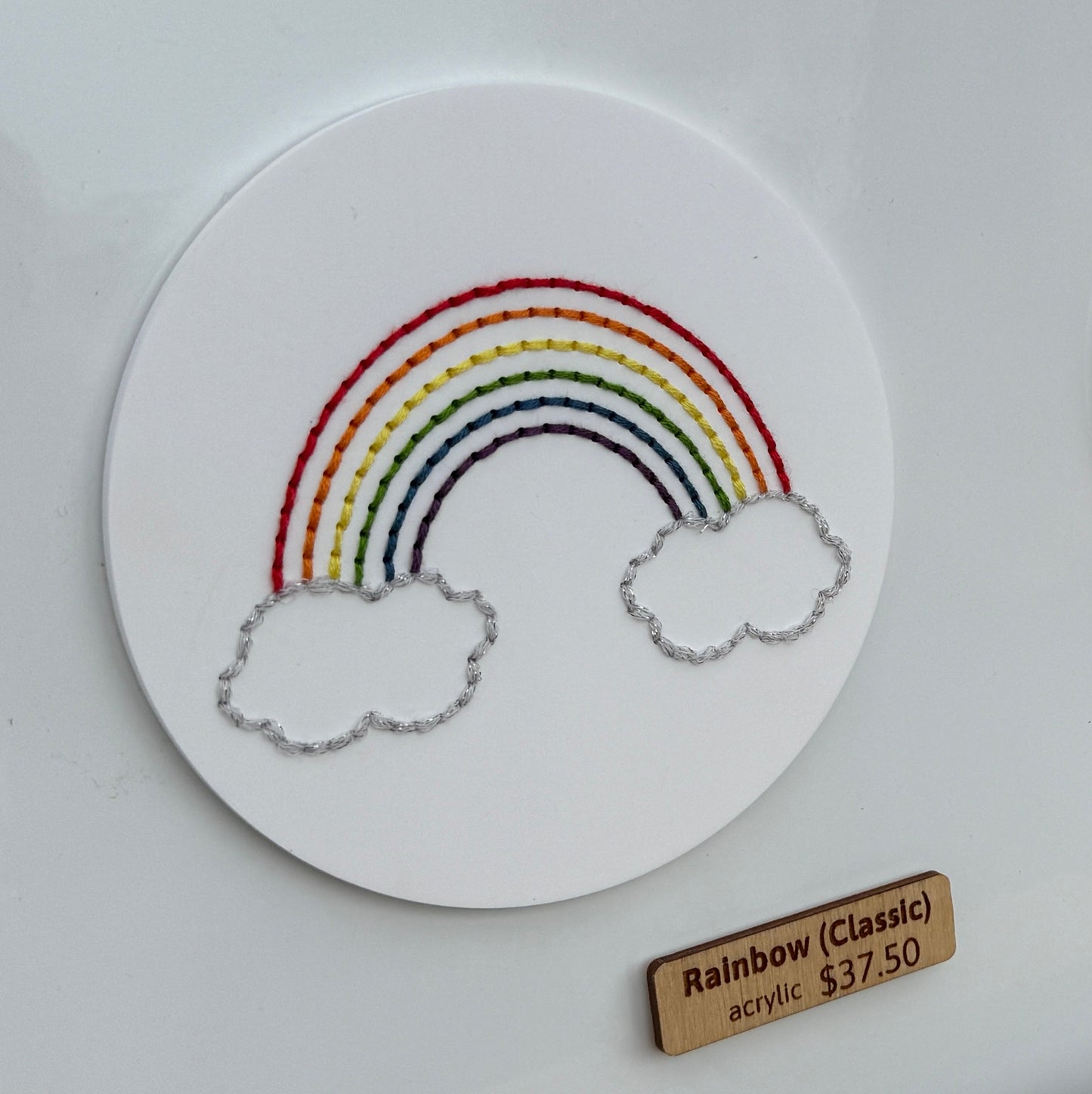 Stitch disk with rainbow adhered to a metal base for market display