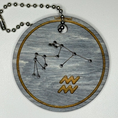 Circular pendant with astrological symbol & stars on a blue wood, set against a white background