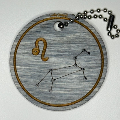 Circular pendant with astrological symbol & stars on a blue wood, set against a white background