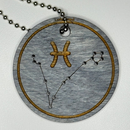Circular pendant with astrological symbol & stars on a blue wood, set against a white background