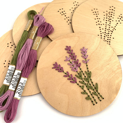 Completed Lavender Sprigs kit laying with purple & green floss on top of a stack of unstitched disks