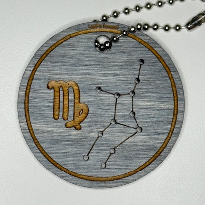 Circular pendant with astrological symbol & stars on a blue wood, set against a white background