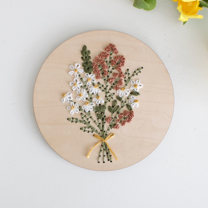 flower bouquet in pink and cream colors embroidered on a wooden disk