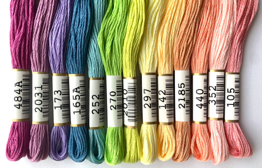 Rainbow palette of Cosmo embroidery floss laid out from soft purple to pink